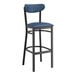 A Lancaster Table & Seating bar stool with a black frame and blue vinyl seat and back.