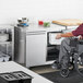 A person in a wheelchair opening an Avantco undercounter freezer.