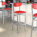 Lancaster Table & Seating Boomerang Series bar stool with red vinyl seat and back on a counter in a cocktail bar.