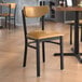 A Lancaster Table & Seating black chair with light brown vinyl seat and back on a table in a restaurant.