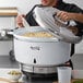 A man using an Avantco natural gas rice cooker to cook white rice in a large pot.