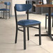 A Lancaster Table & Seating Boomerang Series chair with a navy vinyl seat and back at a table in a restaurant.