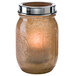 A glass jar with a tealight candle in a gold cradle.