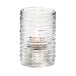 A Hollowick clear glass cylinder candle holder with a lit candle.