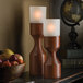 Two Hollowick wood candle holders on a metal surface with fruit.