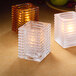 Three Hollowick clear glass jewel square candle holders on a table.