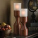 Two Hollowick Denmark tall wood candle holders on a table with candles.