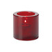 A Hollowick round ruby thick glass tealight candle holder with a lit candle.
