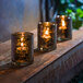 Three Hollowick Antique Black Glass Cylinder Tealights sit on a ledge.