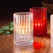 A group of Hollowick clear glass vertical rod candle holders with lit candles on a table.