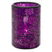 A blue and purple cracked glass cylinder candle holder with a lit candle inside.