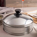 A silver stainless steel dim sum steamer cover.