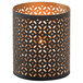 A black metal Monarch votive holder with a gold geometric design holding a lit candle.