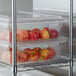 A plastic food storage container filled with red and yellow apples.