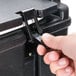 A hand using a black plastic tool to open a black box with a white latch kit inside.