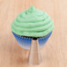 A cupcake with green frosting piped on top using an Ateco plain piping tip.