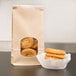 A stack of cookies in a Bagcraft Packaging paper bag with a window and tin tie closure.
