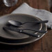 A plate with a Sola Vintage Stonewash stainless steel table fork and spoon on it.