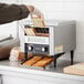 A person wearing gloves puts a piece of bread into a Galaxy conveyor toaster.