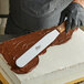 A person using an Ateco straight baking spatula to ice a cake.