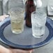 A hand holding an American Metalcraft non-slip tray with glasses of ice water on it.