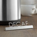 A stainless steel American Metalcraft tabletop sign with "Decaf" laser-cut in it.