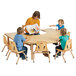 A woman reading a book to children sitting at a Jonti-Craft horseshoe adjustable height table.