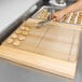 A person using a Footed Cooling Rack on a sheet pan to bake cookies.