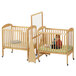 A Jonti-Craft maple wood crib divider with a baby in one crib and a baby in the other.
