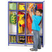 A young boy in a yellow jacket putting clothes in a blue Rainbow Accents coat locker.