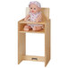 A doll sitting in a Jonti-Craft wooden high chair.