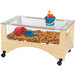 A Jonti-Craft wooden sensory table with a tray of sand and toys.