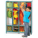 A young boy in a blue shirt putting a yellow jacket in a Rainbow Accents teal coat locker.