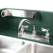 A green Cambro self-contained portable sink with two faucets on a countertop.