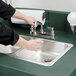 A person using a Cambro green portable self-contained hand sink.