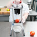 A person in white gloves using a Vollrath InstaCut 3.5 to core a tomato.