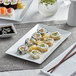 A rectangular bright white porcelain platter with sushi and chopsticks on it.