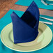 A folded royal blue Intedge cloth napkin on a plate.