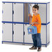 A boy holding a blue lunch bag standing next to a blue and white Rainbow Accents double stack locker.