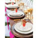 A table set with 10 Strawberry Street porcelain plates and glasses of food.