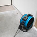 A blue XPOWER axial fan on the floor.
