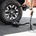 A person using an XPOWER electric duster to clean a tire.