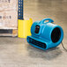 An XPOWER blue air mover on the floor.