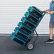 A man pushing a hand truck with several XPOWER XL-730A blue air blowers.