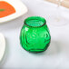 A green glass vase with a circular pattern on a table.