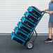 A man pushing a hand truck with several XPOWER blue air movers.