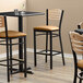 A Lancaster Table & Seating Bistro Bar Stool with a light brown vinyl seat and natural wood back.