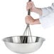 A person using a Thunder Group stainless steel whisk in a bowl.