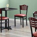 A Lancaster Table & Seating black bistro chair with mahogany wood back and burgundy vinyl seat.
