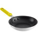 A black frying pan with a yellow silicone handle.